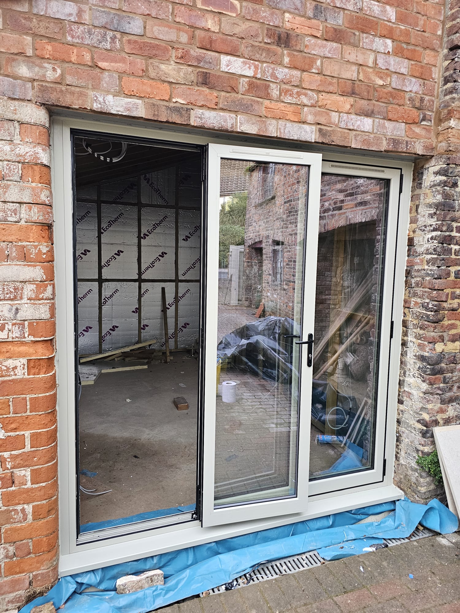 Pebble grey aluminium bifold doors open during installation, installed by WGS Glazing